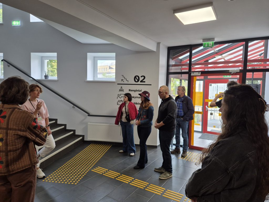 The entrance hall with the glass entrance door, the stairs and a group of visitors.